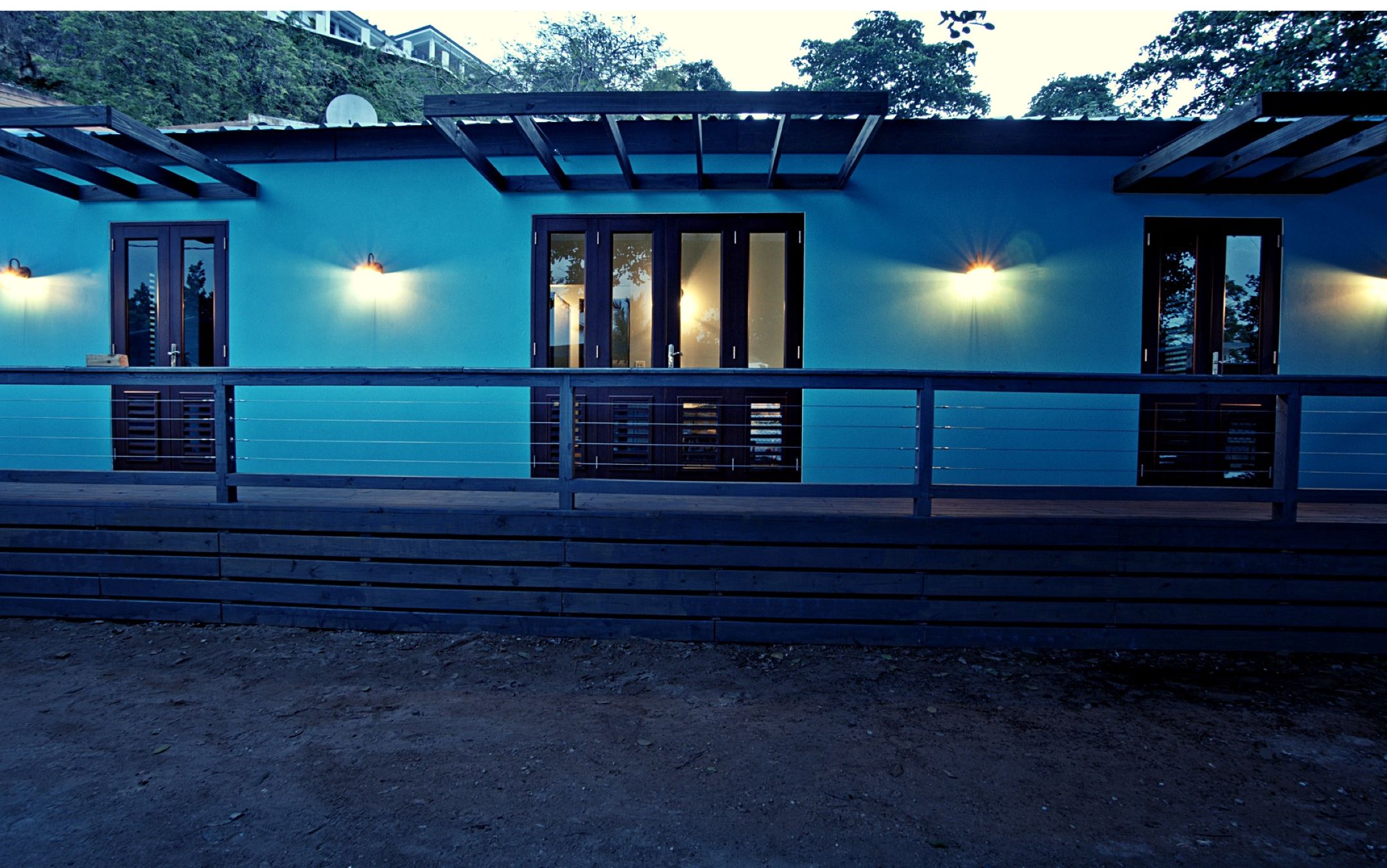 A building with a blue exterior, multiple windows, and a wooden deck in front.