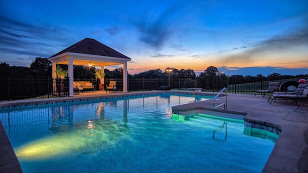A swimming pool with a covered area and lounge chairs.