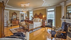 A spacious living room with a large bed, a fireplace, and a chandelier.