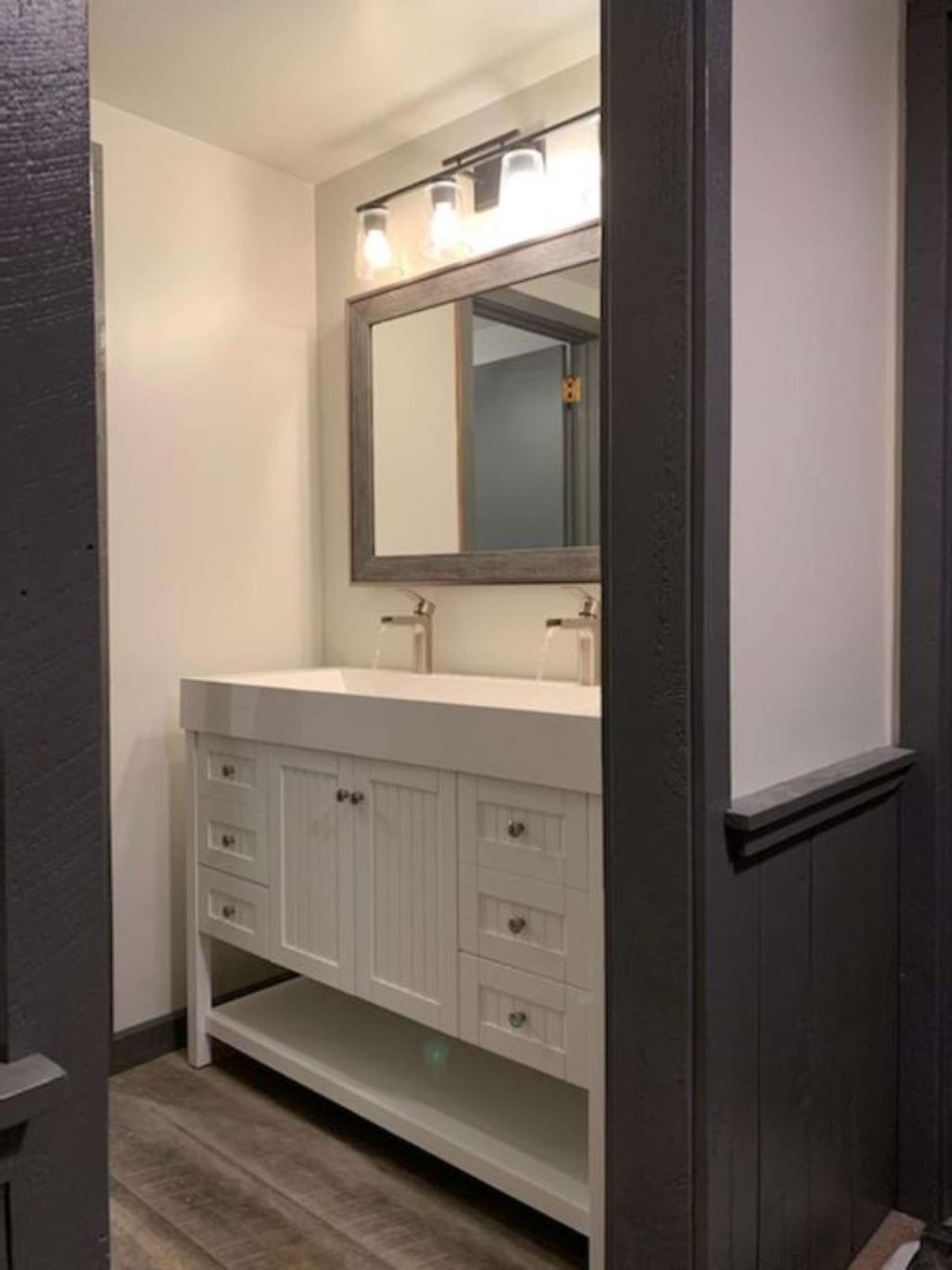 A bathroom with a white vanity, a large mirror, and a lighted vanity area.