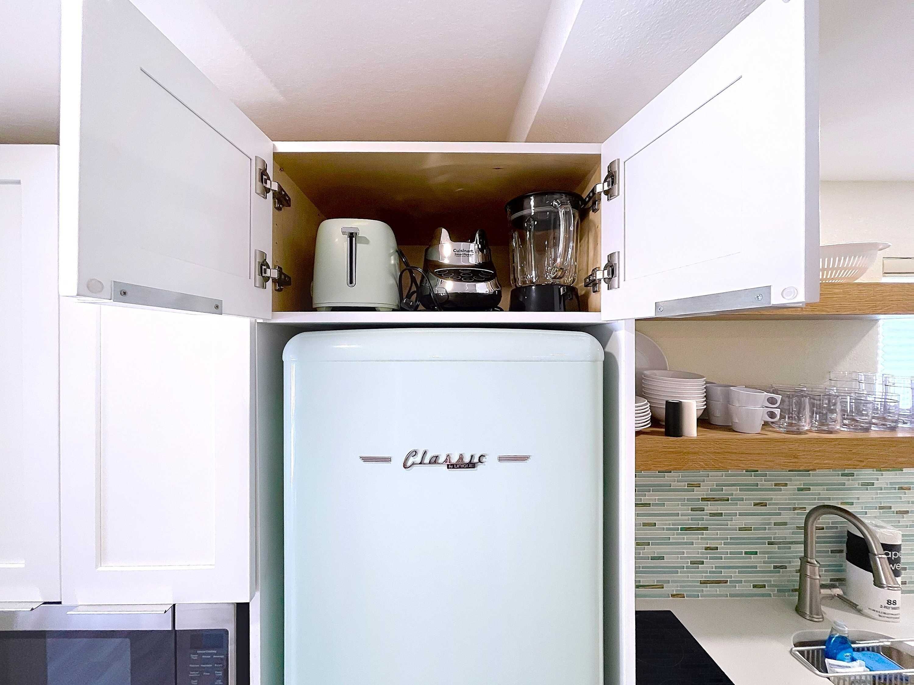 A compact kitchen with a vintage-style refrigerator, a toaster, and a blender.