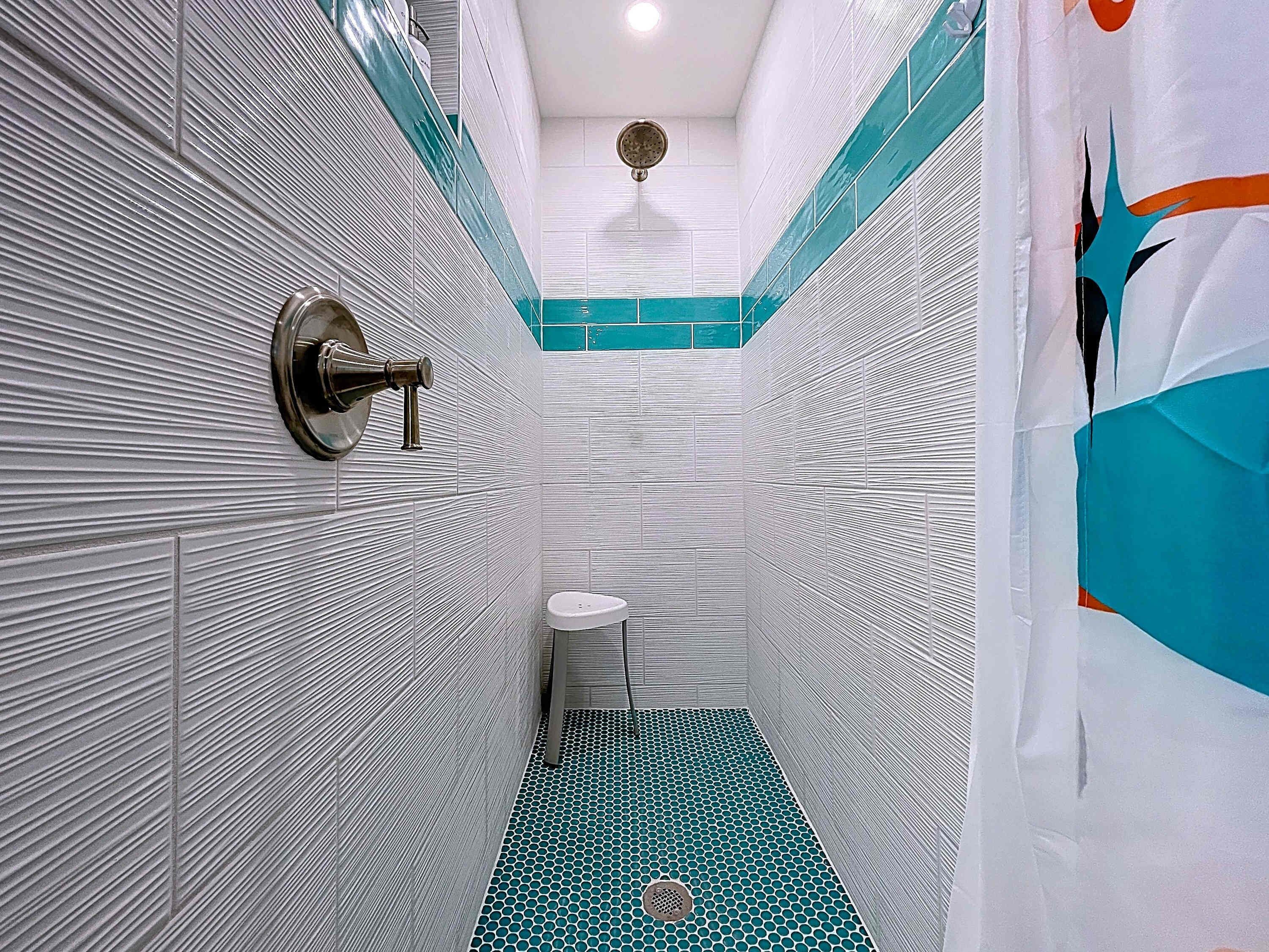 Un baño estrecho con paredes blancas y texturizadas, un lavamanos pequeño y blanco, y un suelo de estampado azul.