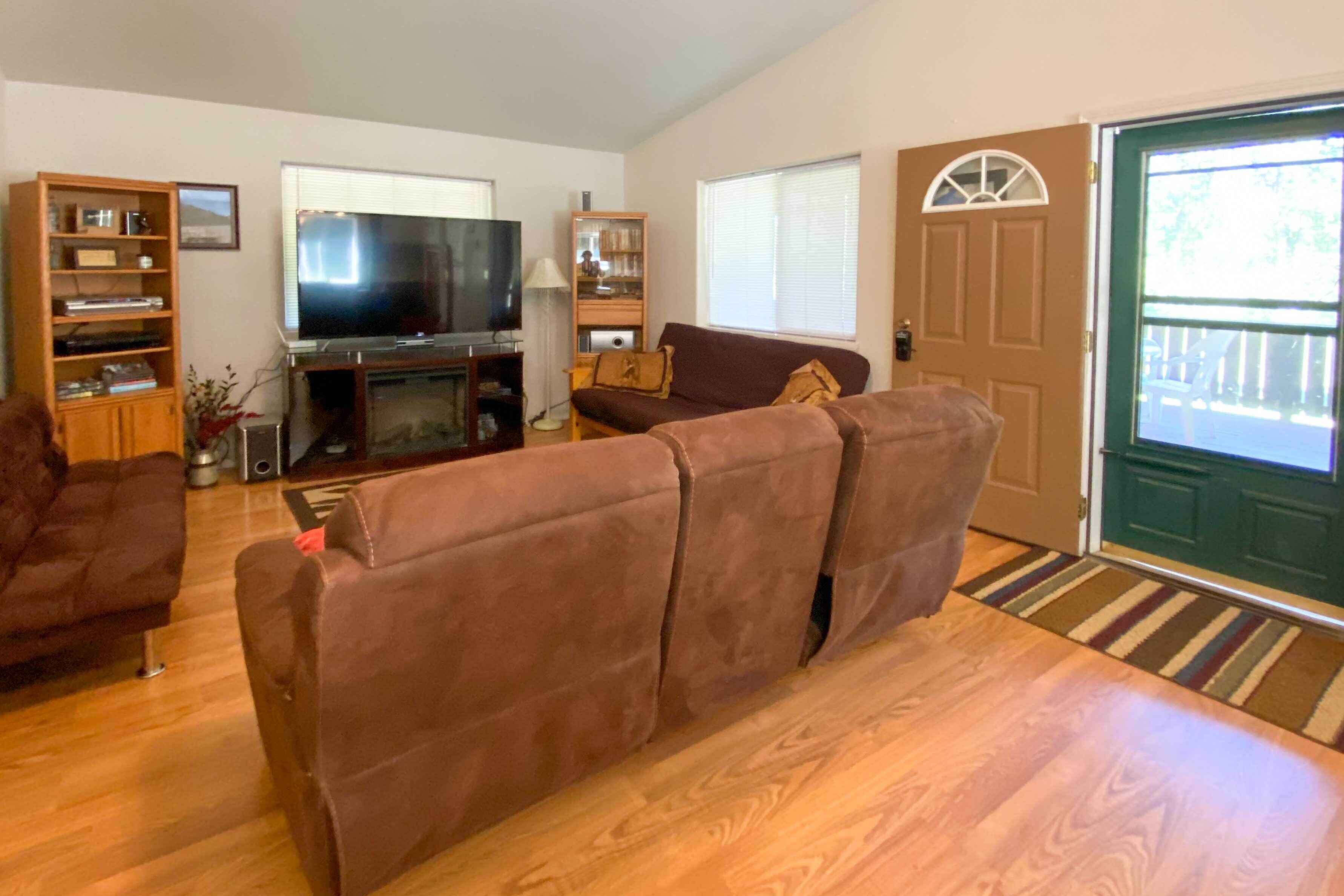 A living room with a brown sofa, a television, and a bookshelf.