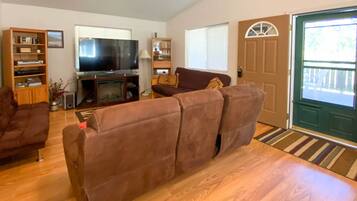 A living room with a brown sofa, a television, and a bookshelf.
