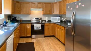 A kitchen with wooden cabinets, stainless steel appliances, and a black rug.