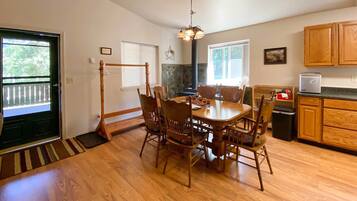 A dining area with a wooden table and chairs, a chandelier, and a kitchen with wooden cabinets.