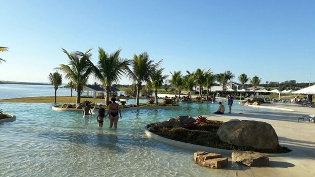 Zona de piscina con agua cristalina, palmeras y ambiente playero.