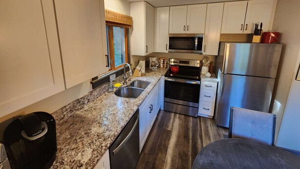 A modern kitchen with granite countertops, stainless steel appliances, and white cabinetry. - ☆ SKI ON & OFF ☆ Spruce Glen B on Great Eastern Trail w/AC, Fireplace, Sauna (Killington)