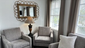 A living room with two armchairs, a side table with a lamp, and a decorative mirror on the wall. - ZenDeck & Courtyard - King Room & Double Room - Pet Friendly - Across from Beach (Charleston)