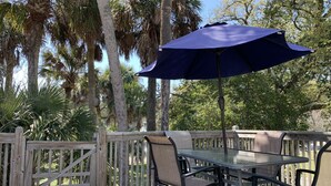 A wooden deck with a glass table and chairs, an umbrella, and a wooden fence. - ZenDeck & Courtyard - King Room & Double Room - Pet Friendly - Across from Beach (Charleston)