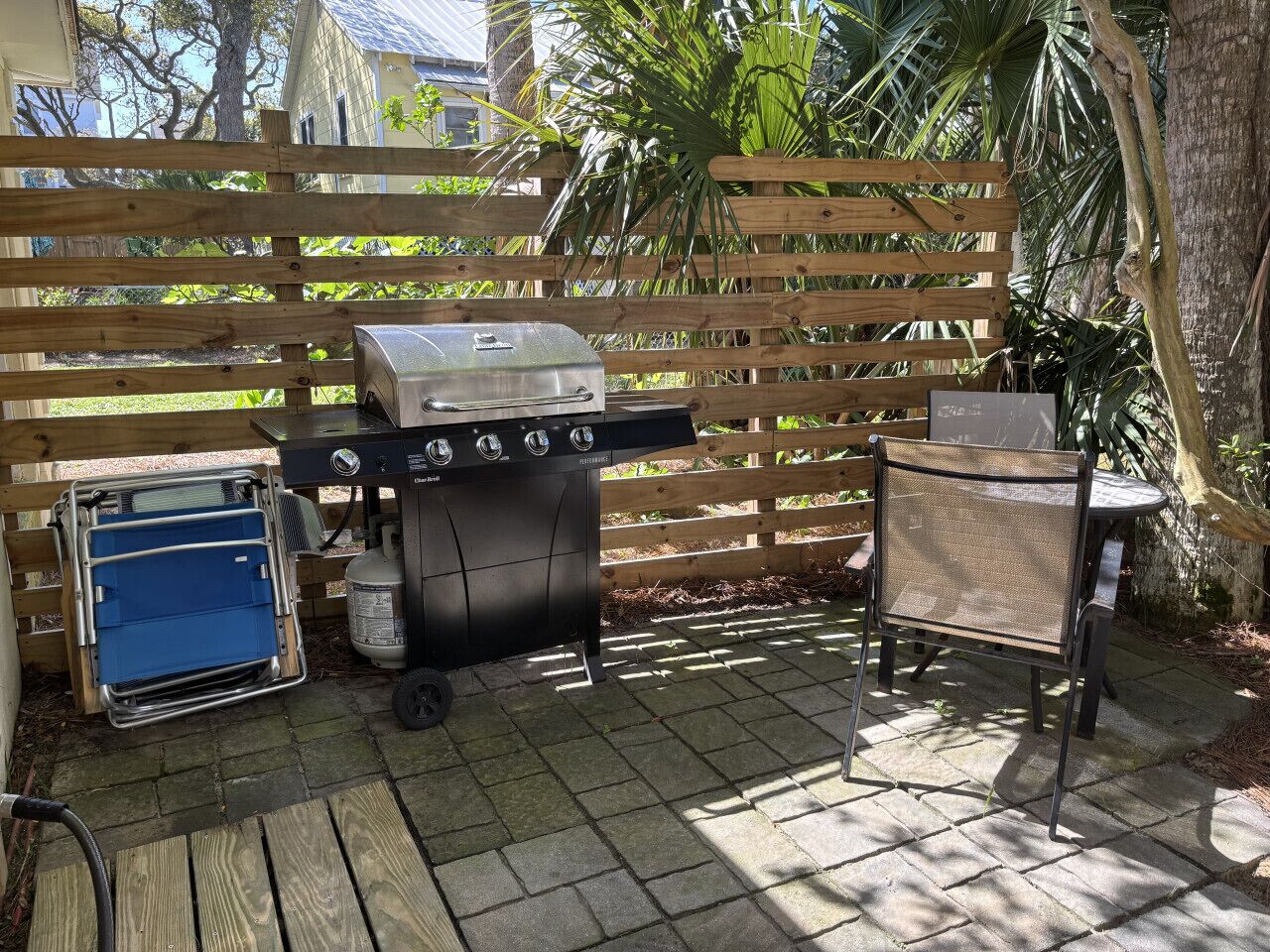 An outdoor patio with a grill, a blue cooler, and a metal table.