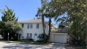 A two-story house with a garage, surrounded by trees and a clear sky. - ZenDeck & Courtyard - King Room & Double Room - Pet Friendly - Across from Beach (Charleston)