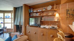 Una sala de estar acogedora con chimenea de ladrillo, televisor y estantería.