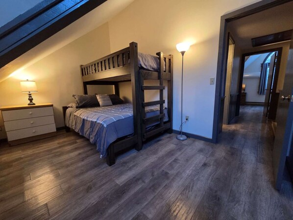 Ein Schlafraum mit Etagenbett, Schreibtisch, Lampe und begehbarem Kleiderschrank.