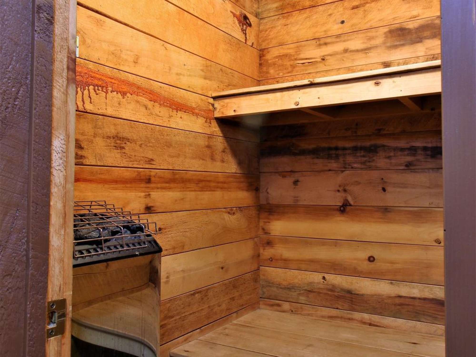 Un interior de madera con un estufa, una puerta y una repisa.