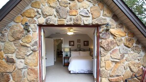 Una habitación con paredes de piedra, una cama, una mesita de noche y una silla.