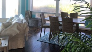 A room with a ceiling fan, a dining table with chairs, a large window, and a plant. - Awesome direct ocean beach house! (cocoa beach)