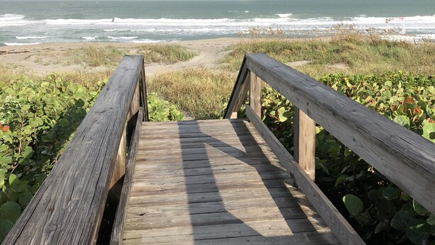 A wooden boardwalk leading to a beach with waves and a rainbow in the sky. - Awesome direct ocean beach house! (cocoa beach)