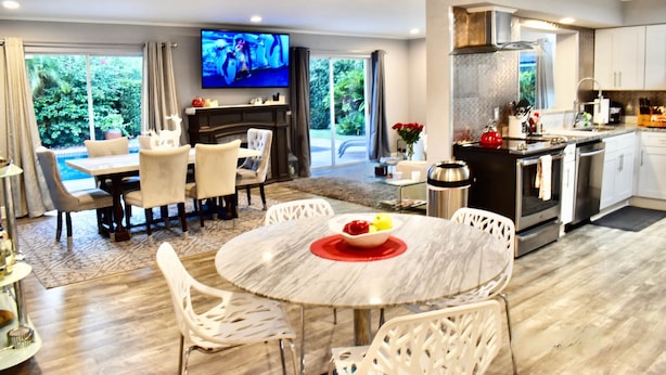 Een moderne woonkamer met een eethoek, een keuken en een televisie.