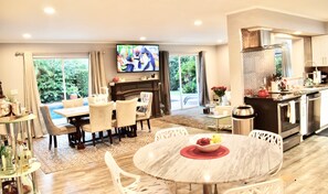 A modern living room with a fireplace, dining area, and kitchen. - Casa Bella (Maitland)