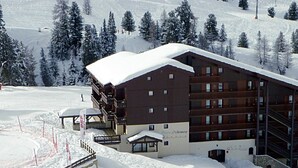 A multi-story building with a snow-covered roof, situated in a snowy mountainous area. - Apartment 2 bedrooms 5/6 people duplex 38m2 at the foot of the slopes (La Plagne Tarentaise)