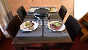 A dining table with plates of food, a glass of water, and a black grill. - Apartment 2 bedrooms 5/6 people duplex 38m2 at the foot of the slopes (La Plagne Tarentaise)