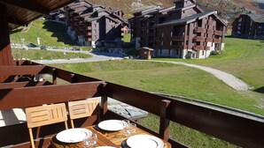 A wooden table set for dining with a view of mountain lodges. - Apartment 2 bedrooms 5/6 people duplex 38m2 at the foot of the slopes (La Plagne Tarentaise)