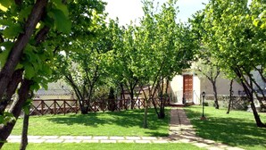 Un camino conduce a un edificio con puerta de madera, rodeado de árboles y un césped cuidado.
