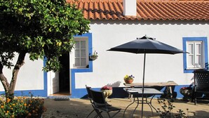 A patio with a table and chairs, a hanging flower pot, and a chimney.