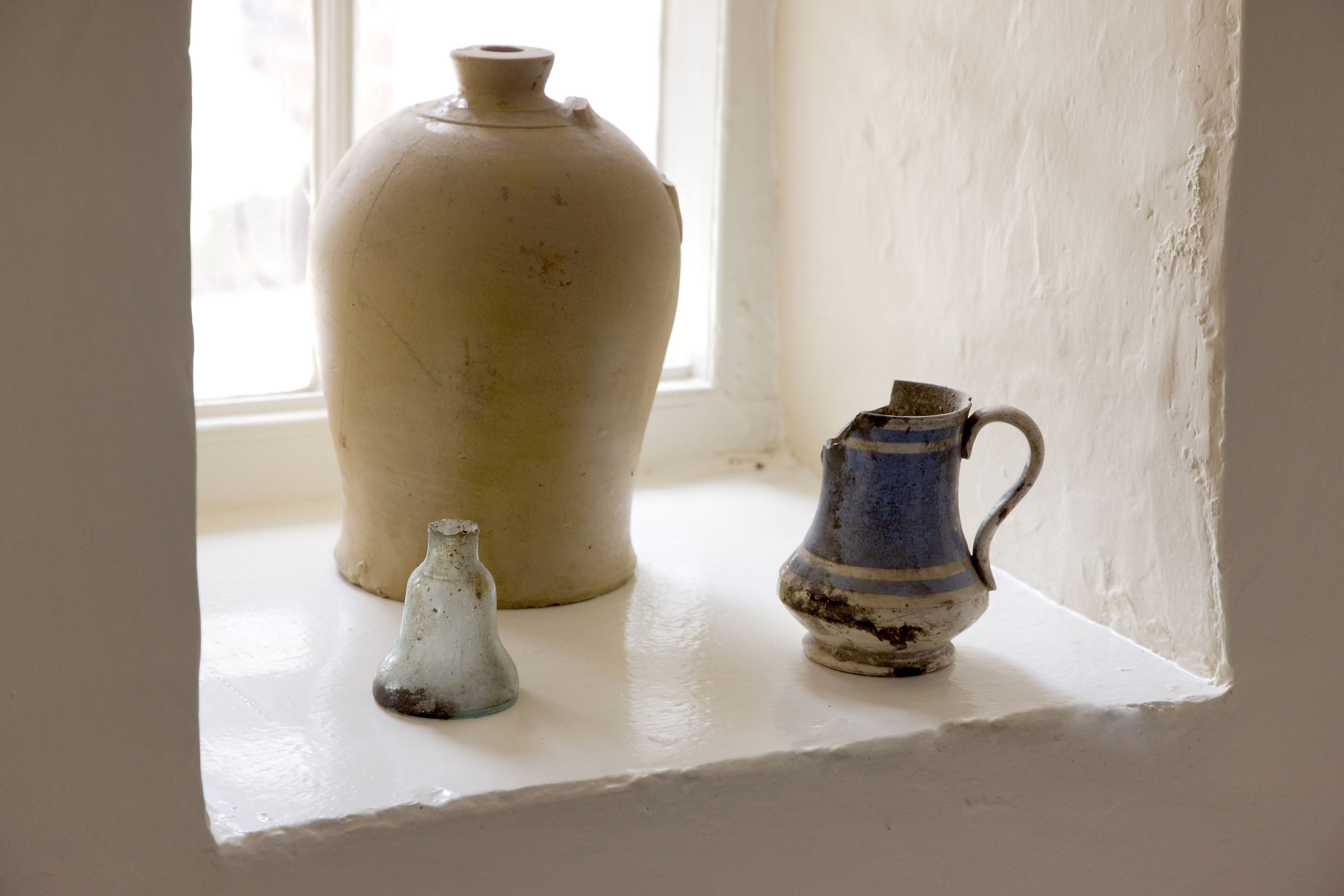 Three ceramic vases on a white ledge by a window.