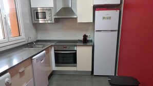 A compact kitchen with a microwave, oven, dishwasher, and a refrigerator.