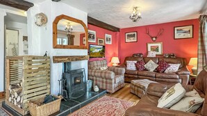 A cozy living room with a fireplace, a sofa, and a television. - Brook Cottage, Challacombe (Challacombe)