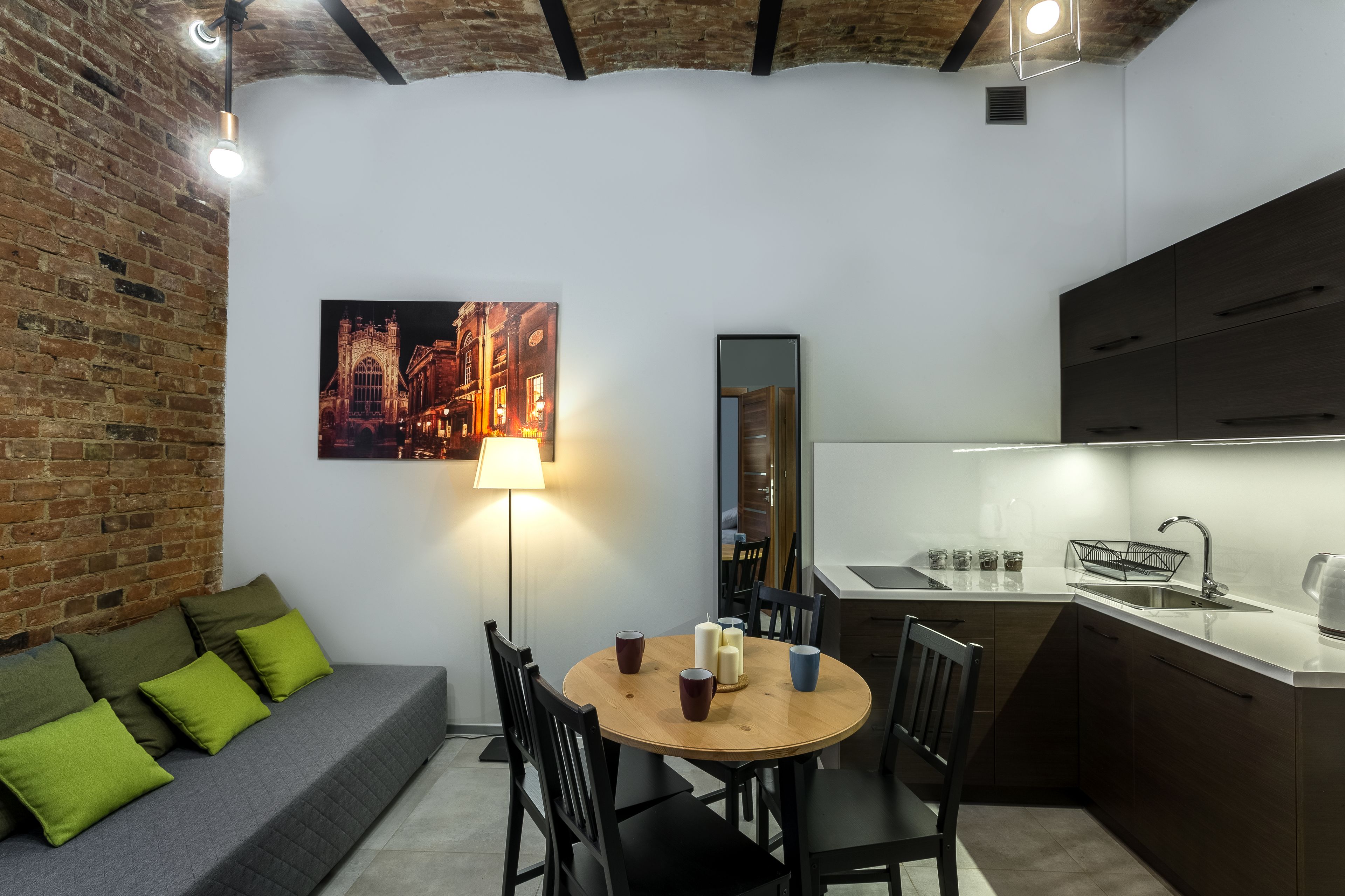 A compact kitchen with a dining area, a brick wall, and a modern light fixture.