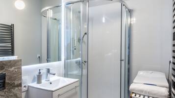 Een moderne badkamer met een douchecabine van glas, een wit wastafelmeubel en een marmeren vloer.