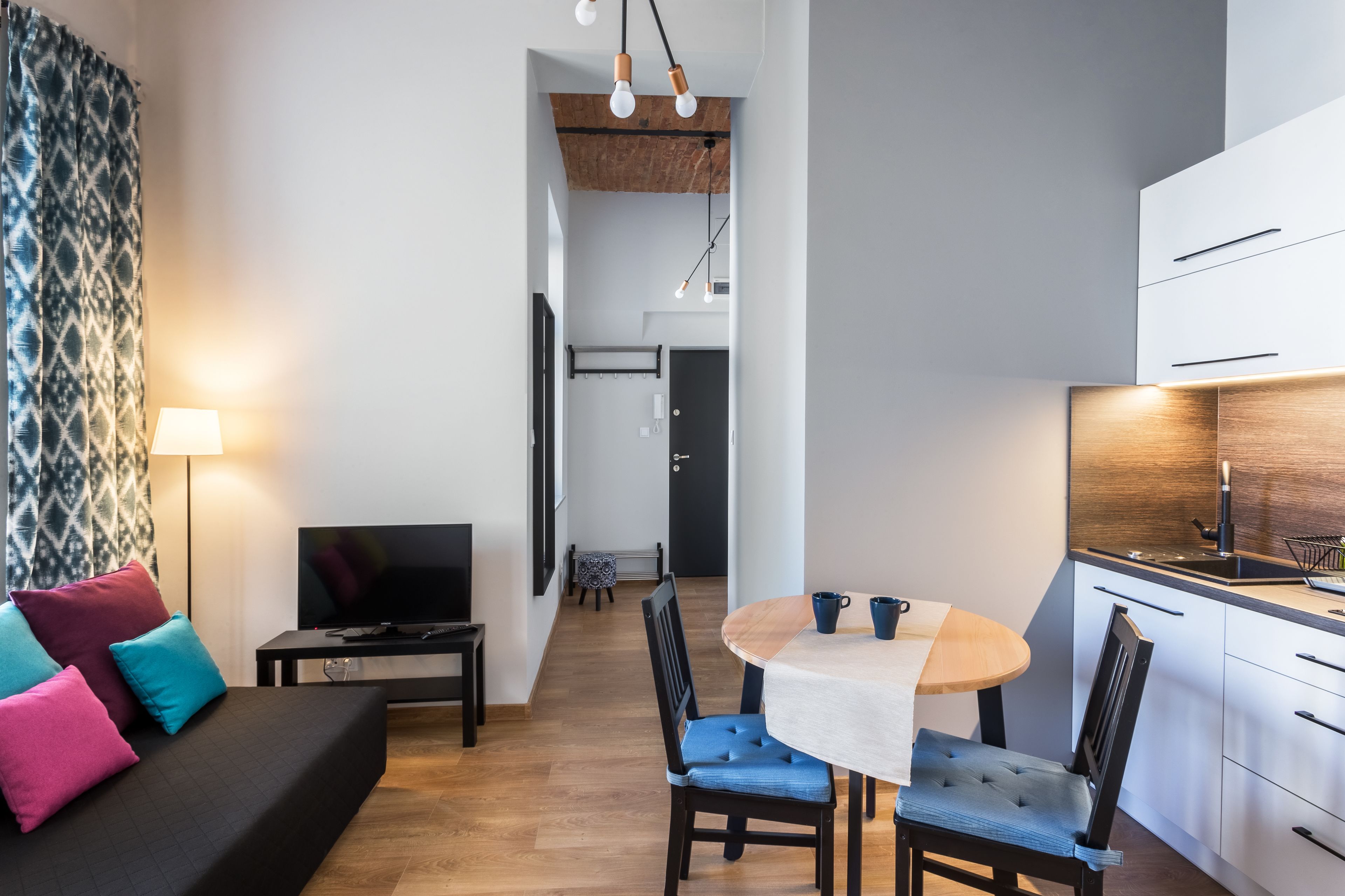 Un salon moderne comprenant un canapé, un téléviseur et un coin repas avec des chaises et une table.