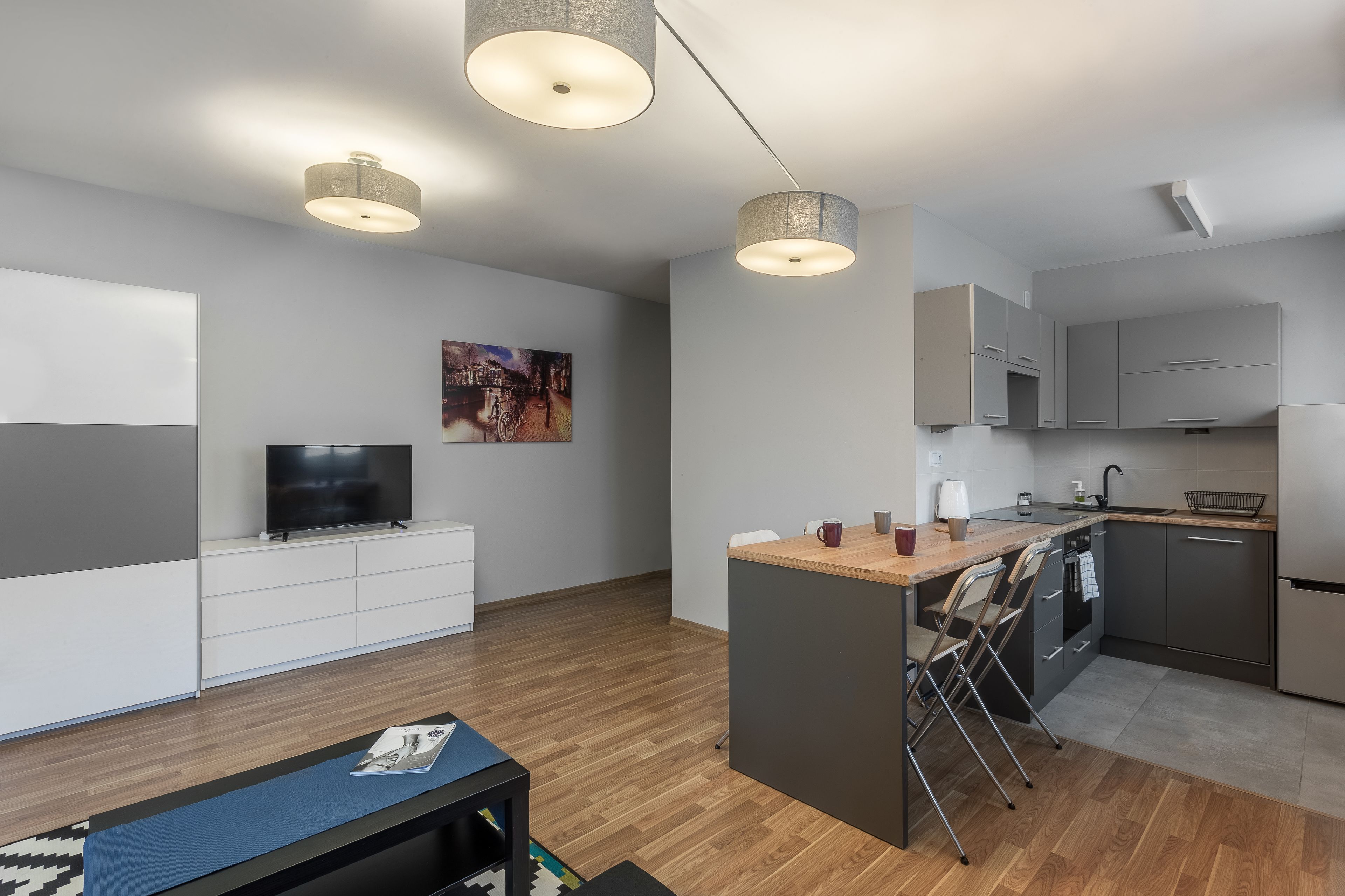 A modern kitchen with a central island, built-in appliances, and pendant lighting.
