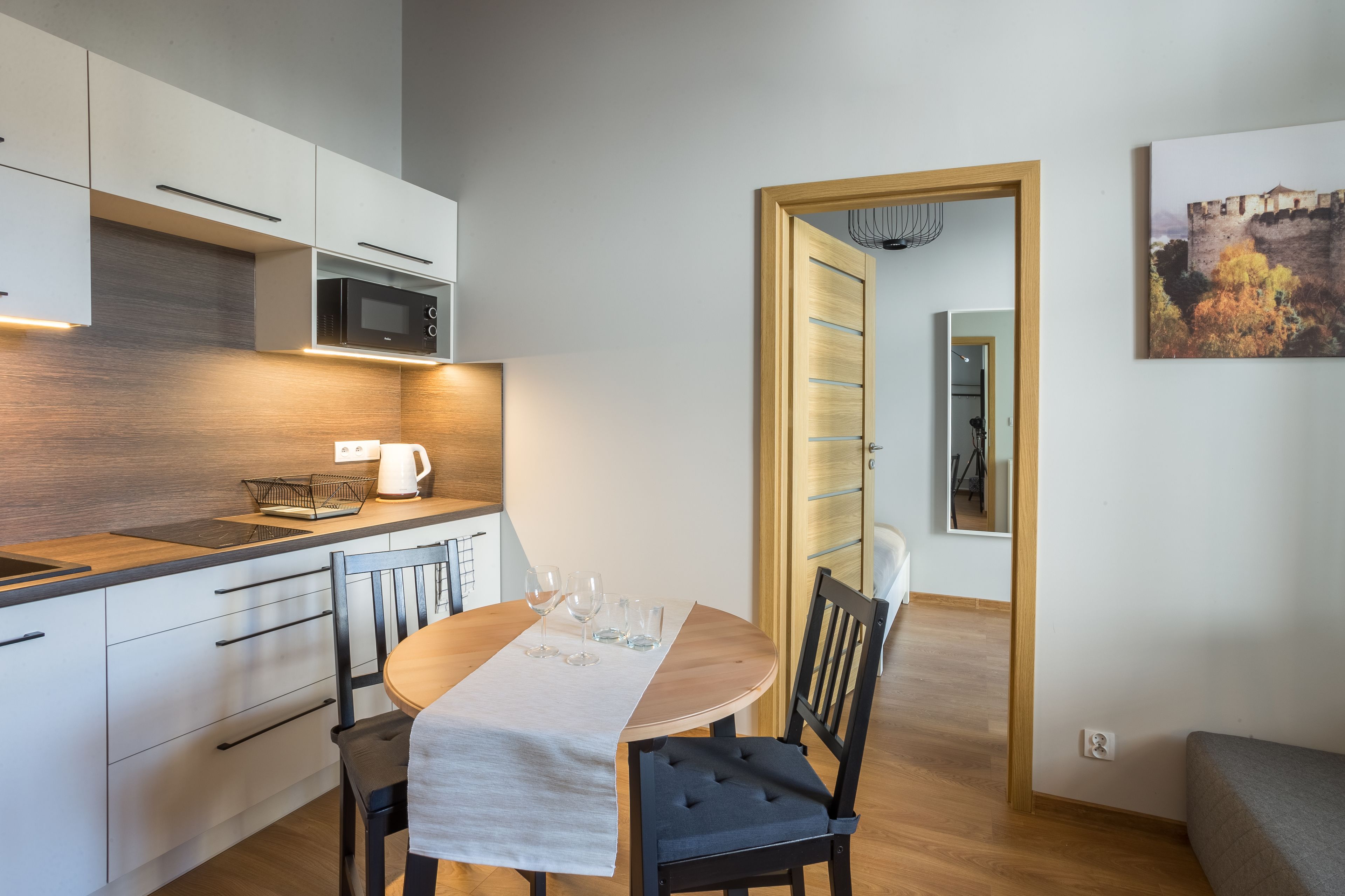 Una cocina moderna con armarios blancos, un microondas y una mesa de comedor con vasos.