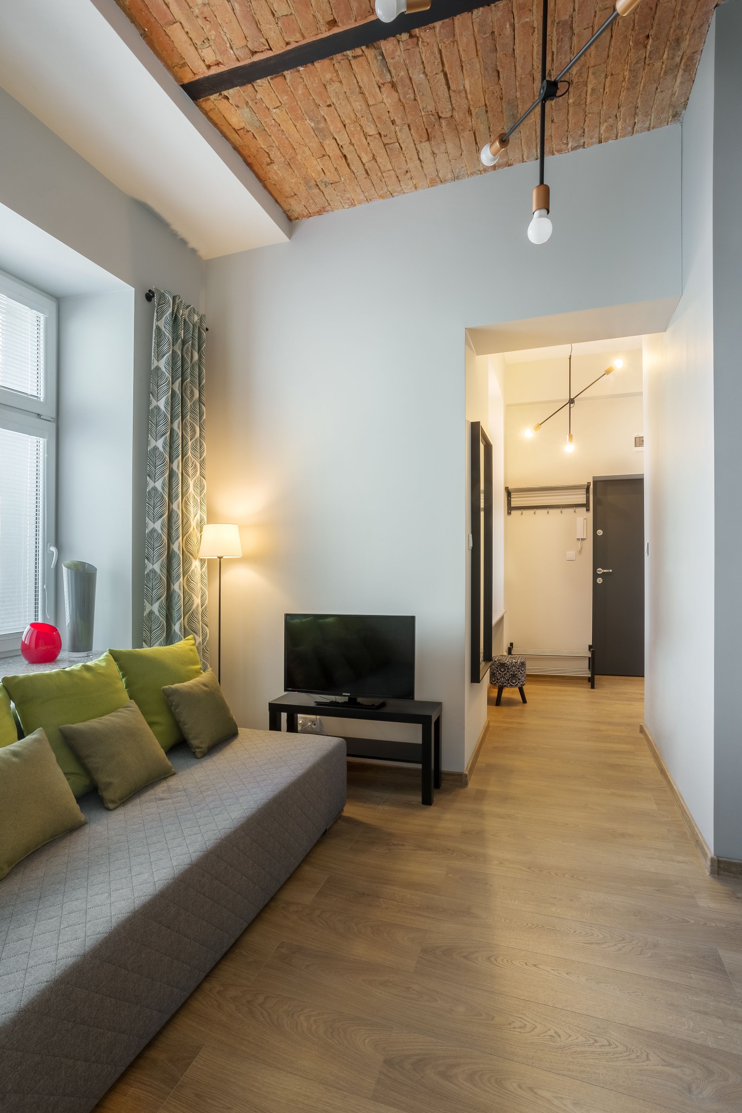 Een moderne woonkamer met een bank, televisie en een houten plafond.