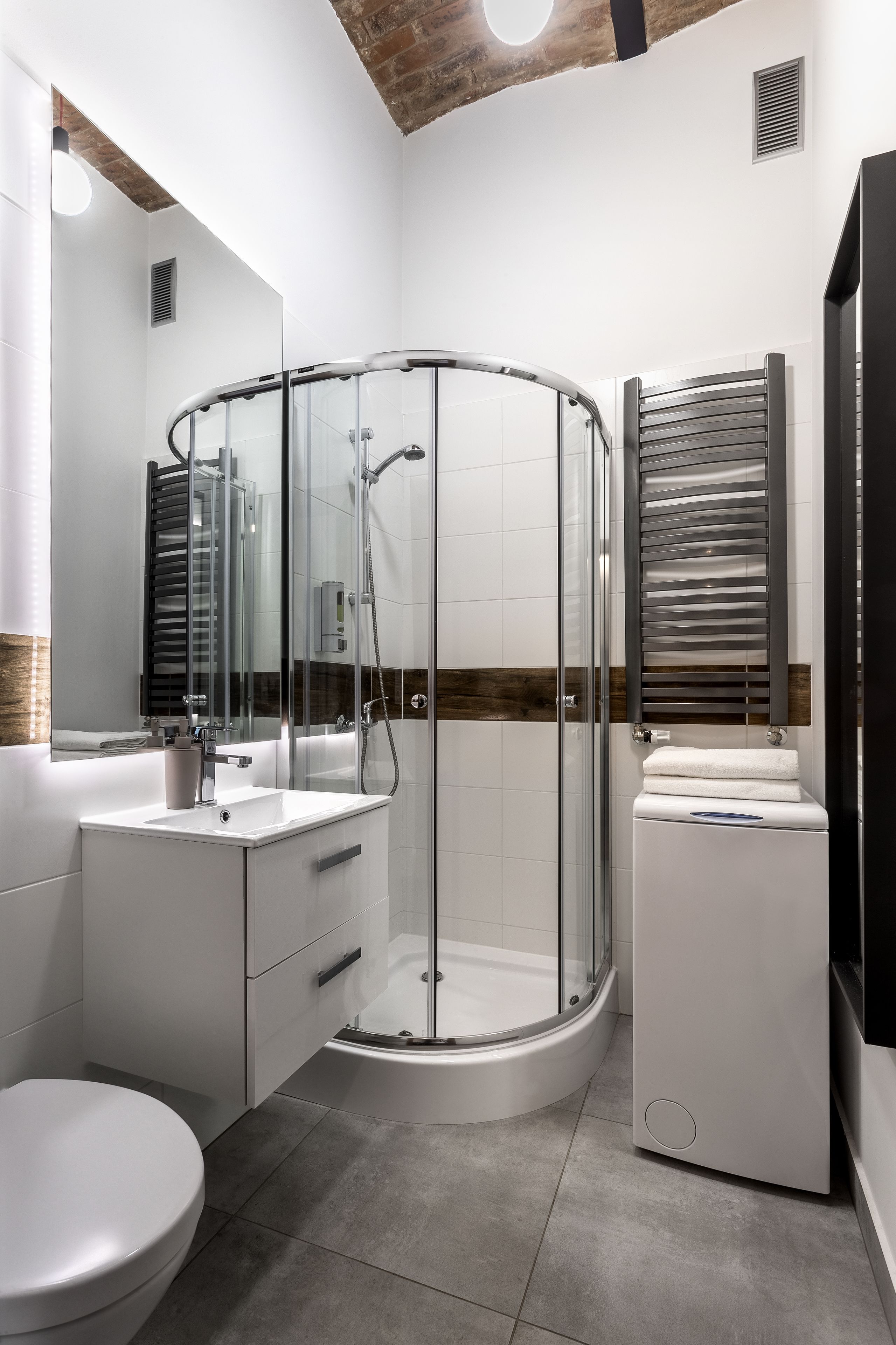 Un baño moderno con ducha de vidrio, lavamanos blanco y un inodoro.