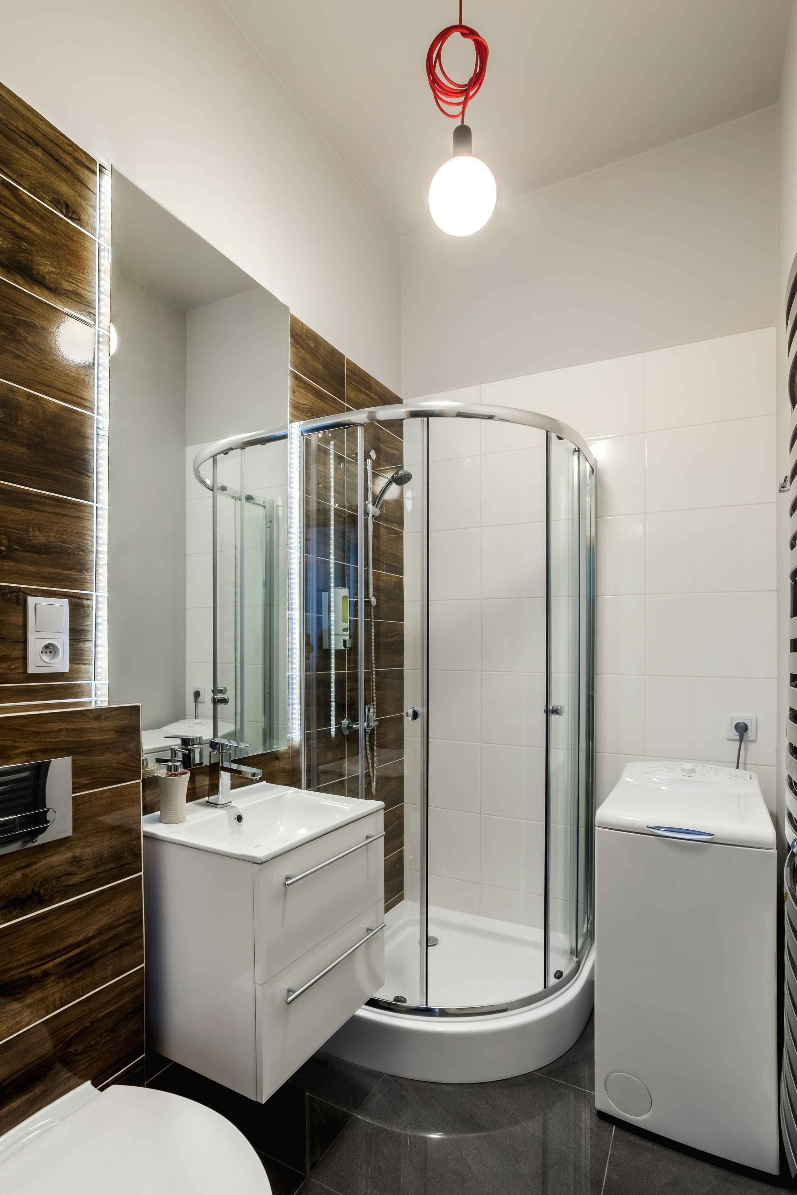 A modern bathroom with a glass-enclosed shower, a white sink, and a toilet.