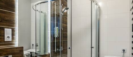 A modern bathroom with a glass-enclosed shower, a white sink, and a toilet.