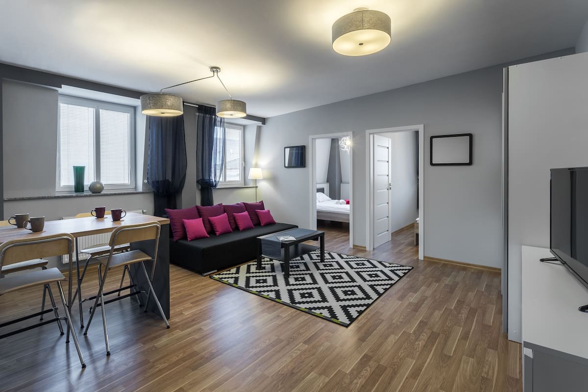 En moderne stue med sofa, spisebord, stole og et fjernsyn.