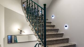 A spiral staircase with a green metal railing and built-in lighting.