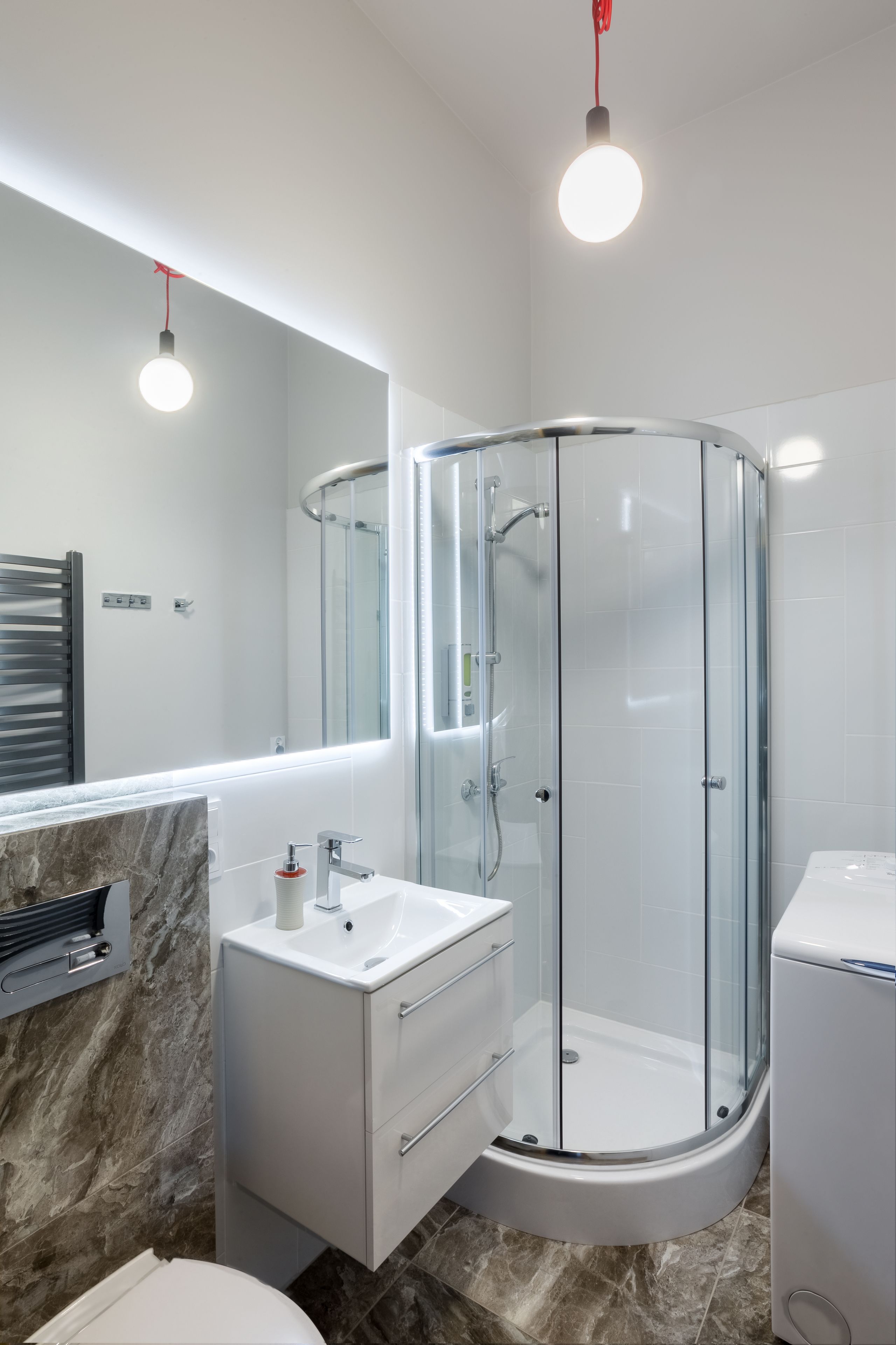 A modern bathroom with a glass-enclosed shower, a marble sink vanity, and a large mirror.