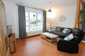 Uma sala de estar aconchegante com um sofá, mesa de centro e uma janela com cortinas.