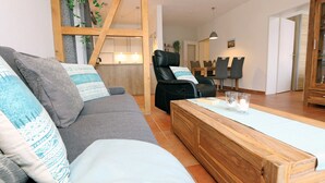 A modern living room with a sofa, a wooden coffee table, and a black leather chair.