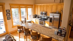 Una cocina con armarios de madera, encimeras de granito y un refrigerador de acero inoxidable.