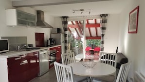 Une cuisine compacte avec un îlot central, des chaises blanches et une table à manger.