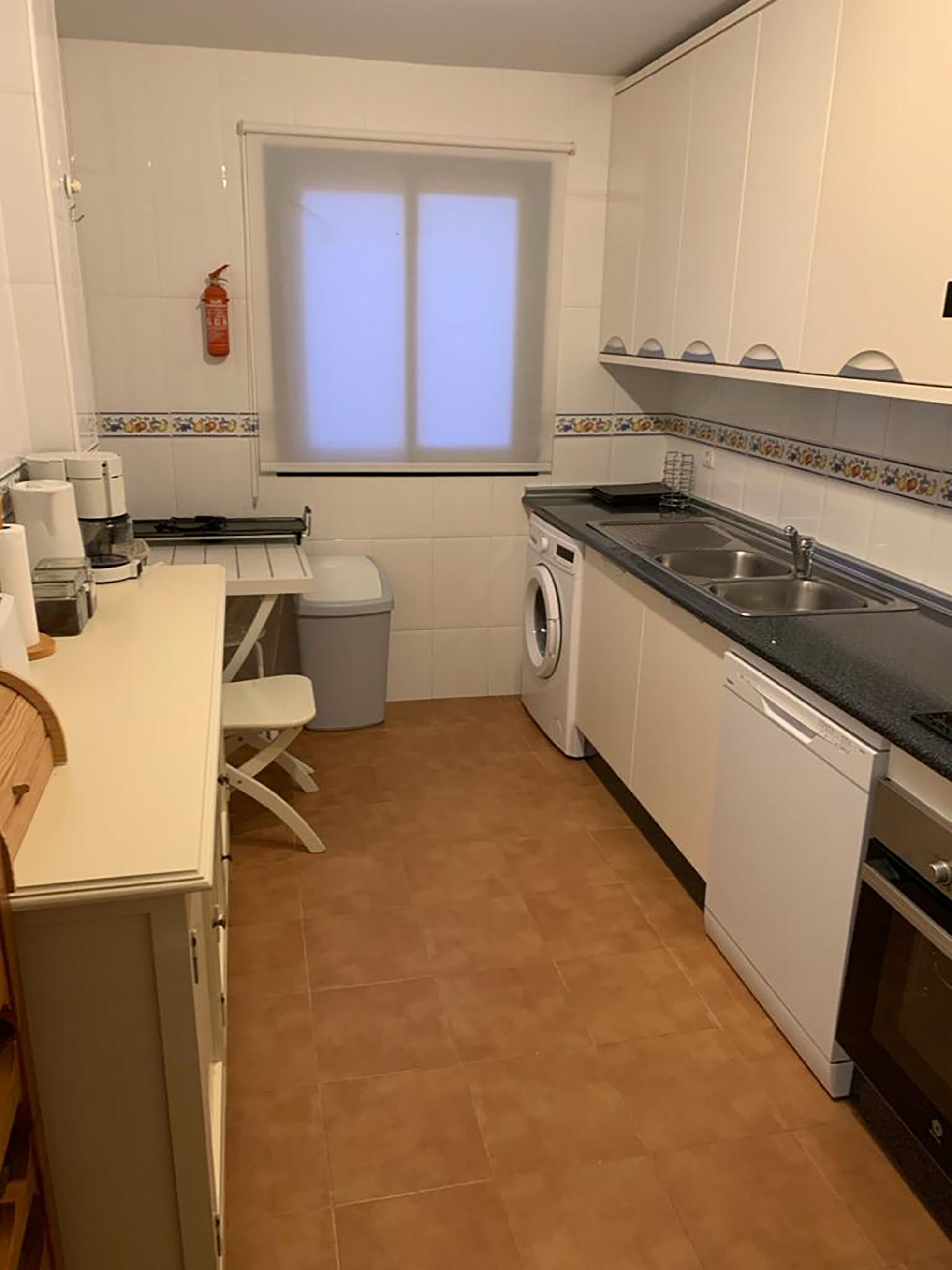 Une cuisine compacte équipée d’un lave-linge, d’un évier et d’une machine à café.