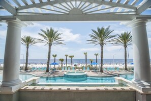 Un espace piscine agrémenté de palmiers et offrant une vue sur la plage.
